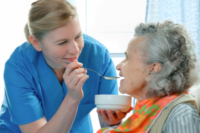 caregiver helping senior woman to eat